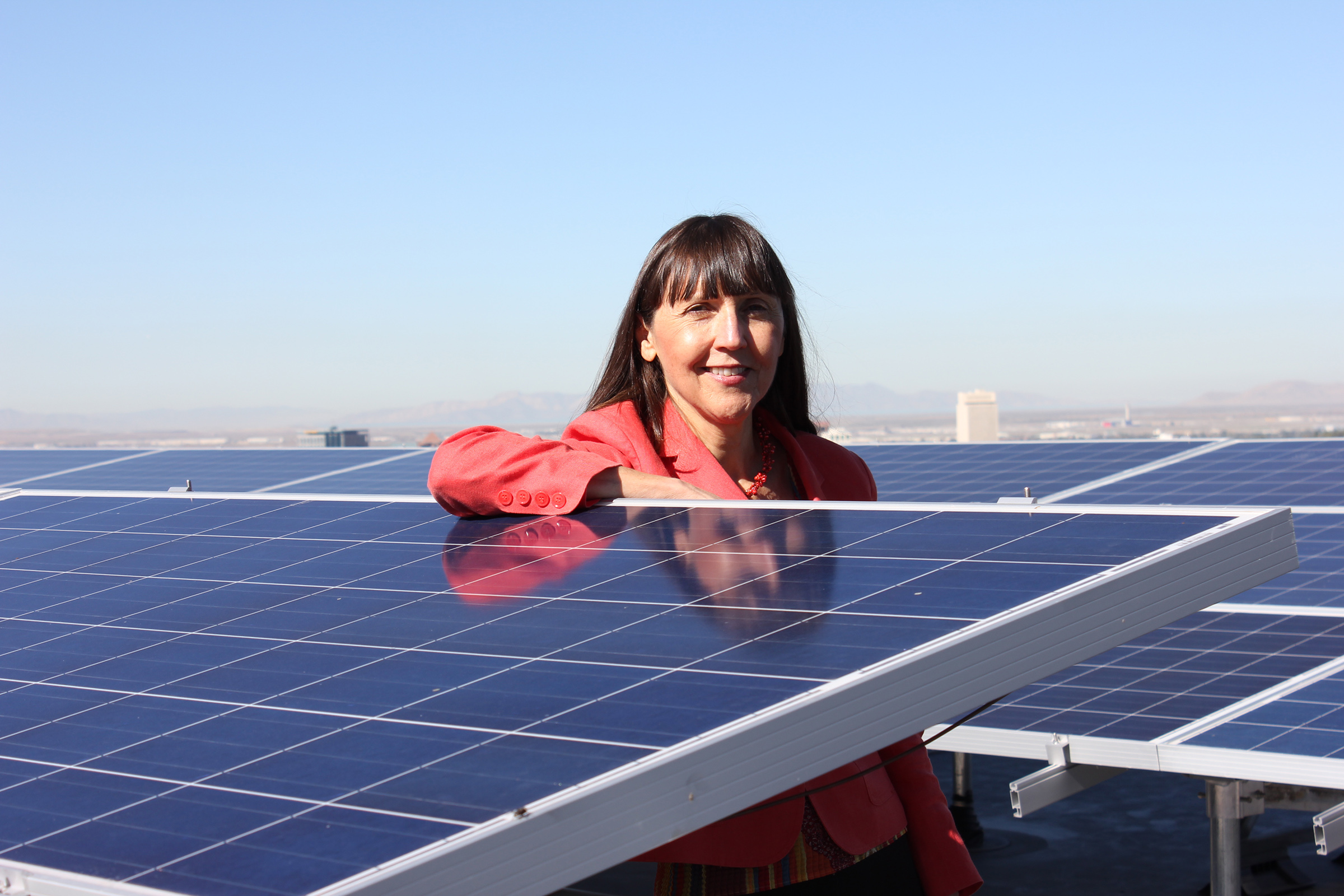 Alberta Comer, dean of the J. Willard Marriott Library and university librarian, poses next to one of the six solar arrays on the library roof.