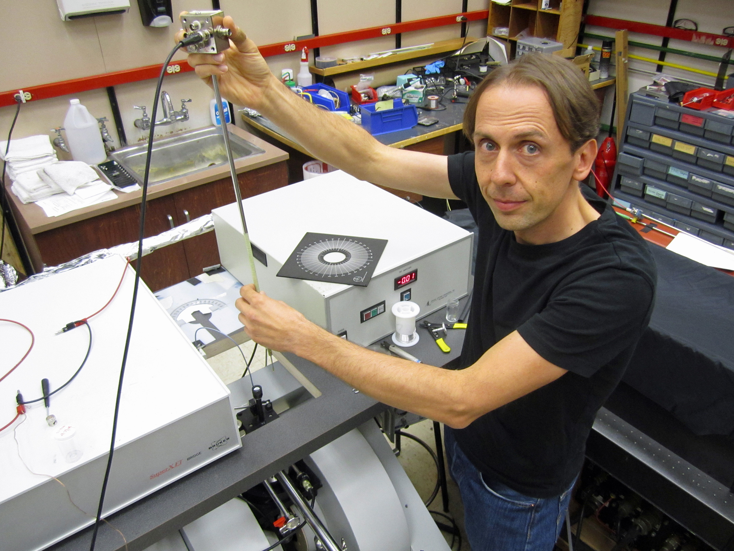 University of Utah physicist Christoph Boehme works in his laboratory on an apparatus used in a new study that brings physics a step closer to “spintronic” devices such as superfast computers, more compact data storage devices and more efficient organic LEDs or OLEDS than those used today for display screens in cell phones, computers and televisions. The study, published in the Sept. 19 issue of the journal Science, showed the physicists could read the subatomic “spins” in hydrogen nuclei and use the data to control current that powers light in a cheap, plastic LED, or OLED, under practical operating conditions.