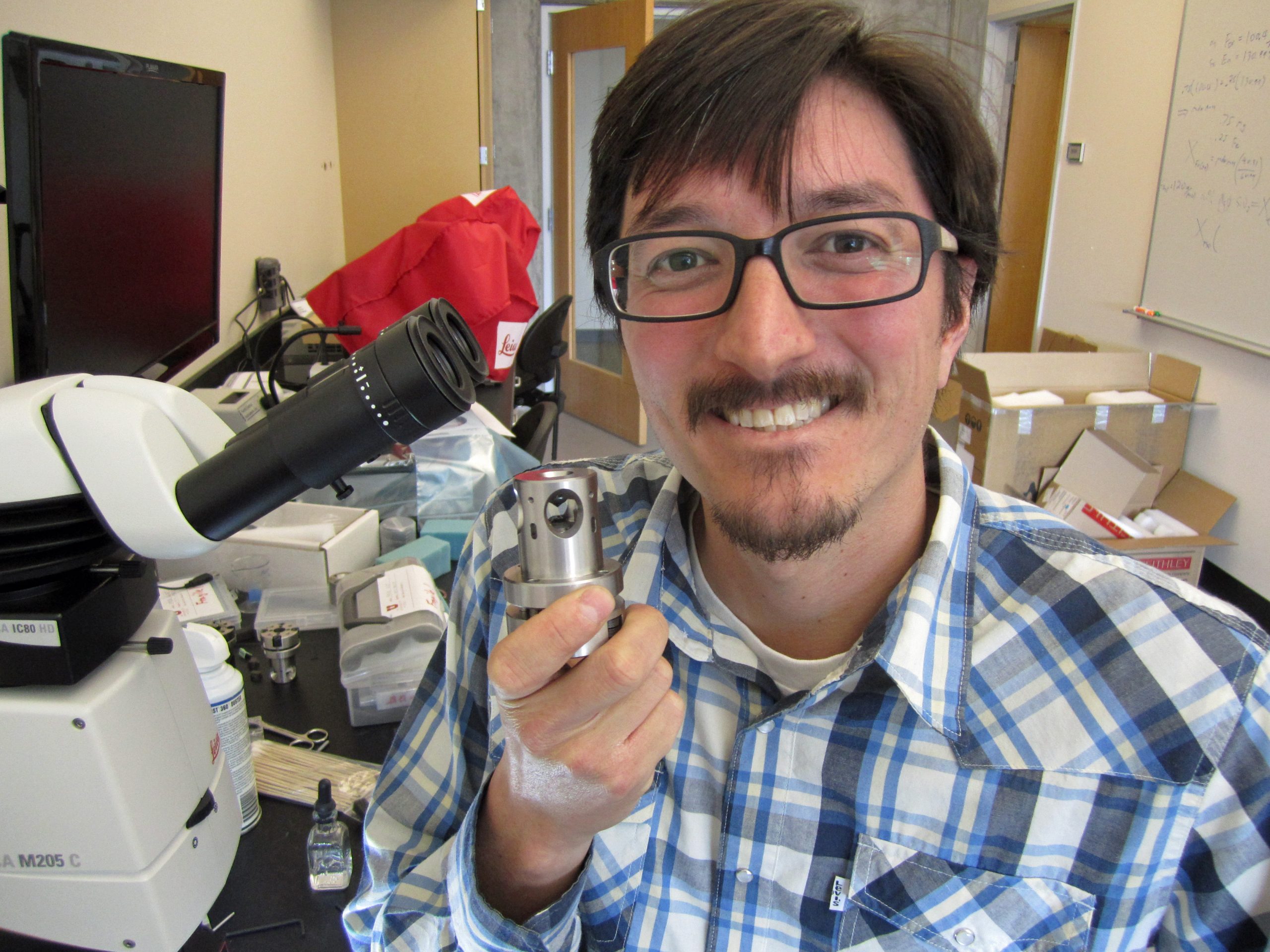 University of Utah geophysicist Lowell Miyagi holds a press that houses a diamond anvil, in which minerals can be squeezed a pressures akin to those deep within the Earth. Miyagi and a colleague in Germany squeezed mineral crystals in a diamond anvil under pressures like those deep underground. Their findings suggest the existence of a previously unknown layer of extremely stiff or viscous rock 930 miles underground in the top part of Earth’s lower mantle. Such a layer would explain why seismic images have shown slabs from Earth’s sinking tectonic plates sometimes stalling and thickening or pooling at that depth.