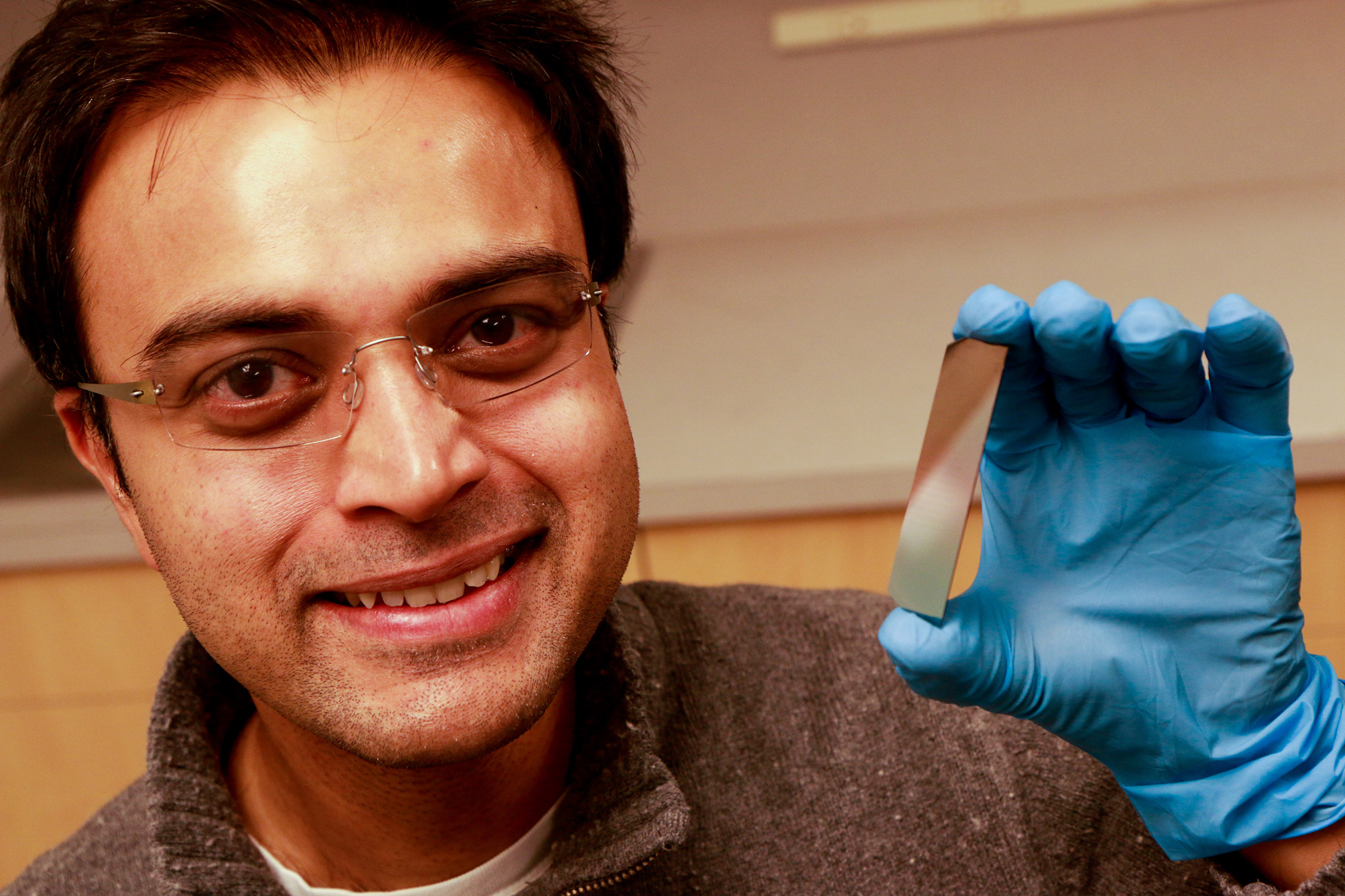 University of Utah electrical and computer engineering associate professor, Rajesh Menon, holds up a piece of silicon that has been etched with microscopic pillars and holes to create a polarized filter. He leads a team of researchers that have developed a new polarizer that can allow more light to pass through than conventional polarizers. This could lead to LCD displays for smartphones and tablets that last longer on a battery charge and cameras that can take better pictures at low light.