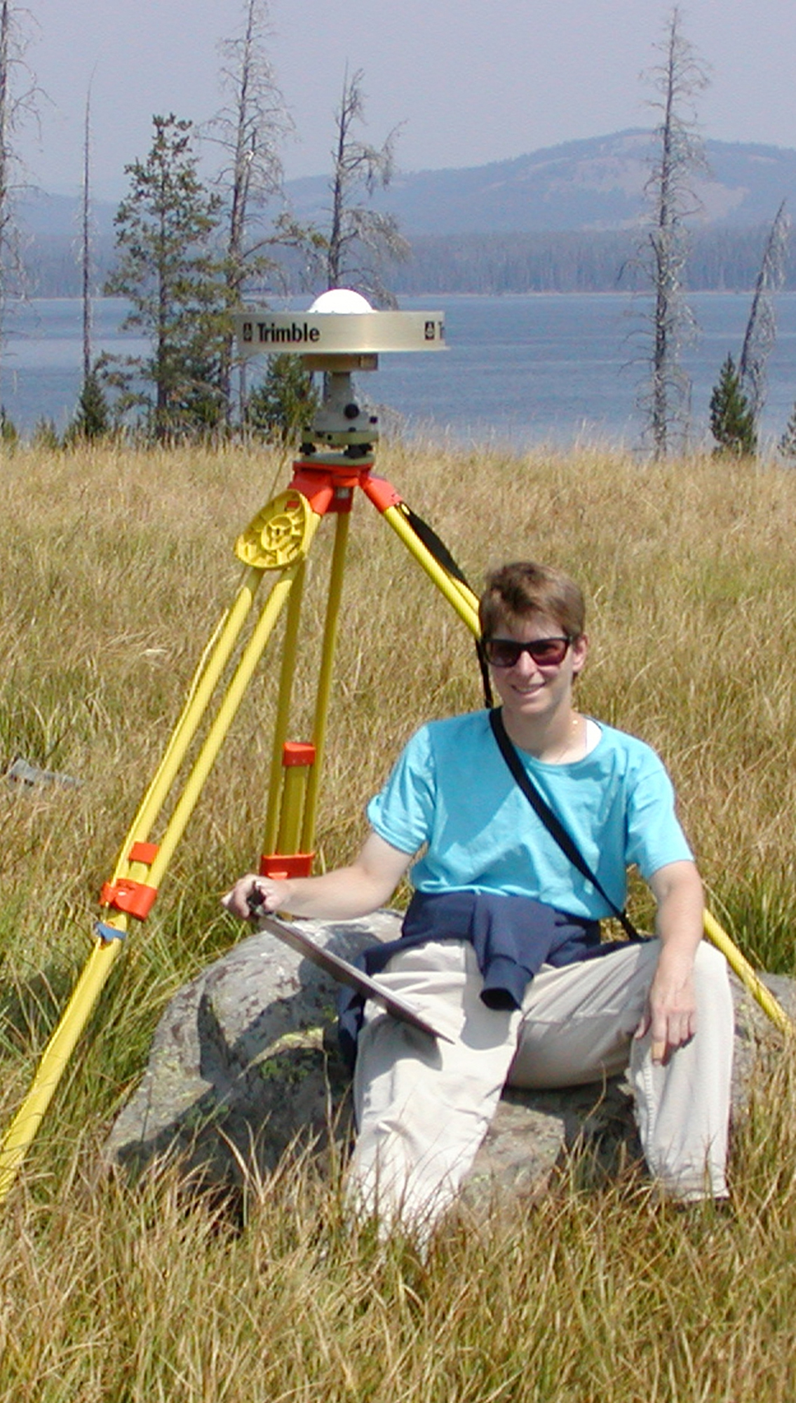 Christine Puskas, a University of Utah doctoral student in geophysics, sits by a portable Global Positioning System (GPS) antenna near the shore of Yellowstone Lake in Wyoming. Puskas, Utah geophysicist Robert B. Smith and others have published a study based on 17 years of GPS measurements showing how Earth's crust in a large region of the West is deformed by the Yellowstone hotspot, a giant plume of hot and molten rock that powers Yellowstone's hot springs and geysers, generates earthquakes and occasionally produces catastrophic volcanic eruptions.